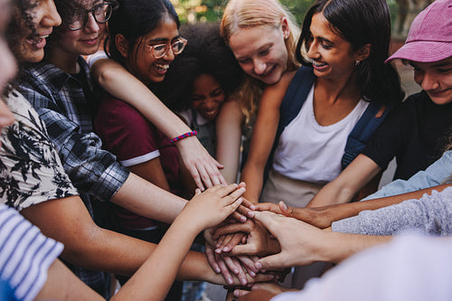 Cheerful teenagers putting their hands together in solidarity