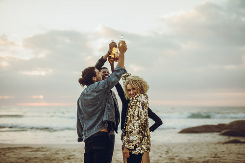 Friends celebrating with beers at the beach