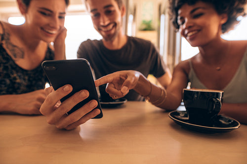 Friends looking at smart phone in cafe