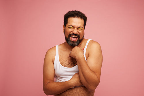 Confident genderqueer smiling on pink background