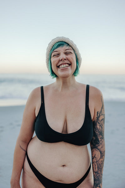 Female winter bather smiling with her eyes closed at the beach