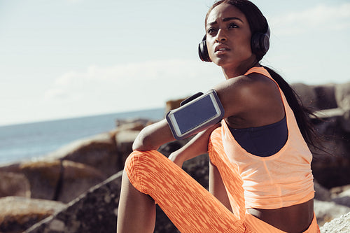 Woman runner sitting at seaside after workout