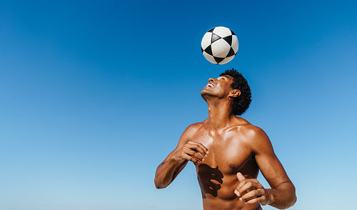 Brazilian man showcasing impressive football skills under a bright blue sky