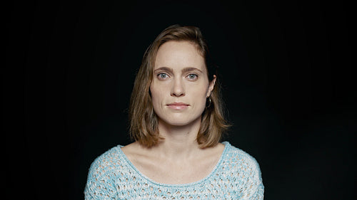 Woman with blank expression on black background