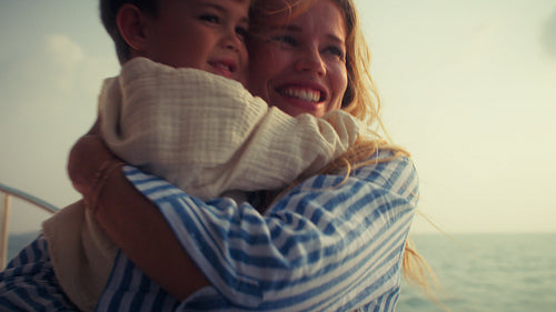 Loving embrace between mom and young boy on a sunny boat journey