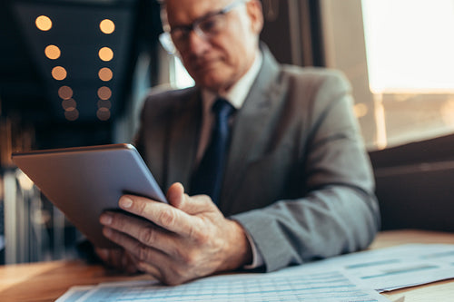 Businessman at cafe working on digital tablet.