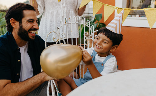 Father celebrating child's birthday outdoors with decorations and fun activities