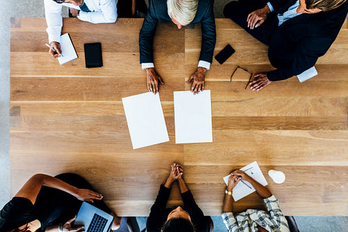 Corporate professionals meeting around a table with blank pages