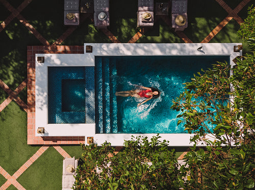 Top view of a young tourist woman floating in a pool
