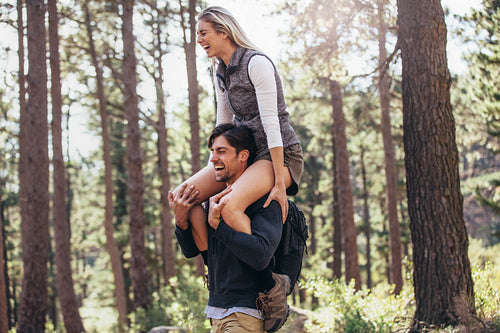 Man carrying his woman partner on his shoulders while trekking in forest