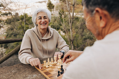 Mature couple playing a game of chess together outdoors