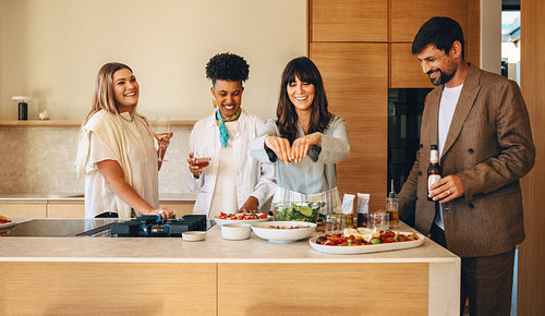 Friends enjoying drinks and cooking together in a stylish modern kitchen