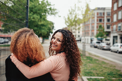 Young woman walking with her friend along city street