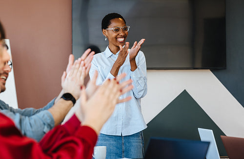 Smiling team applauding a speaker during a meeting in a modern office