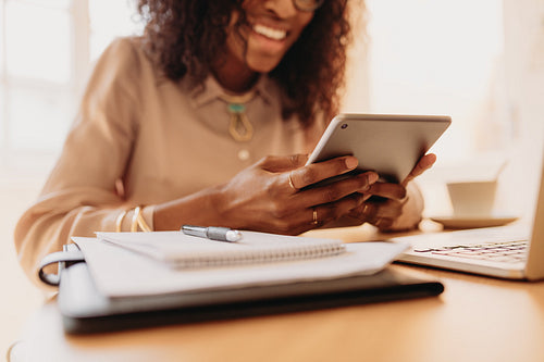 Businesswoman looking at tablet pc while working on laptop at home