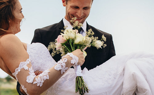 Happy groom carrying beautiful bride
