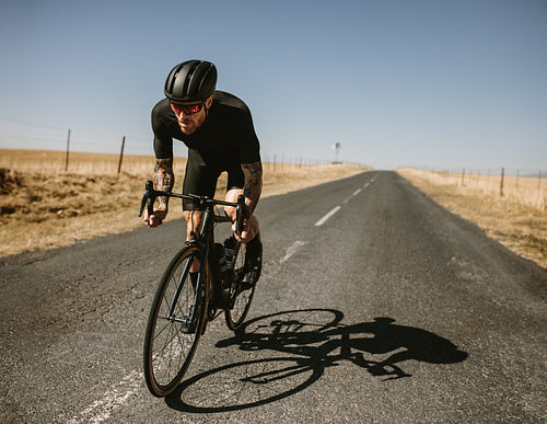 Athlete riding a bike on asphalt road