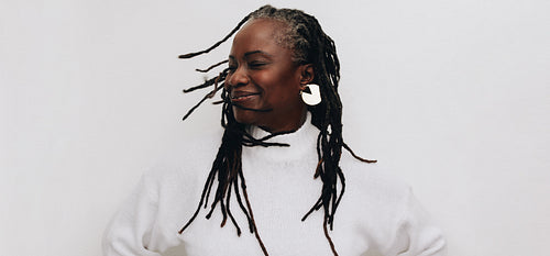 Happy mature woman whipping her dreadlocks in a studio