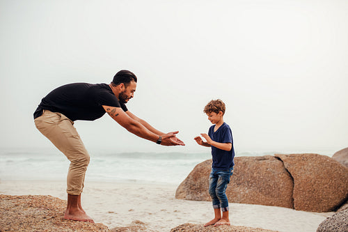 Father and son playing on the rocky beach