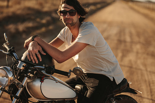 Man sitting on a vintage motorcycle outdoors