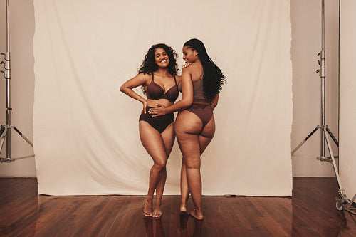 Cheerful female friends standing in brown underwear