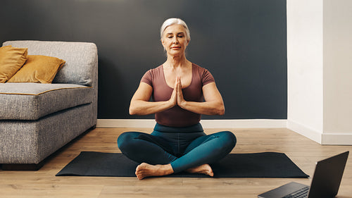 Mindful woman practicing prayer pose during online yoga session