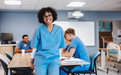 Happy nursing student looking at the camera in a teaching hospital, wearing medical scrubs