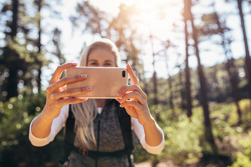 Woman hiker taking photograph in forest