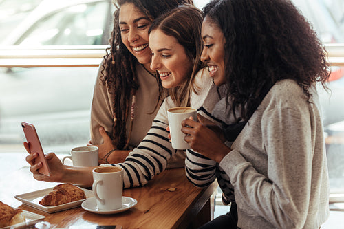 Friends sitting in a cafe looking at mobile phone