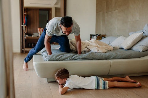 Father and son playing hide and seek in bedroom