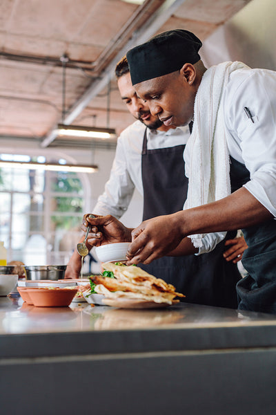 Chefs preparing food together in restaurant kitchen