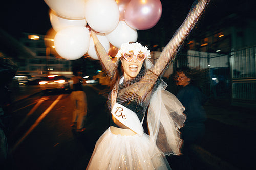 Woman celebrates wearing costume and balloons during festive night event outdoors