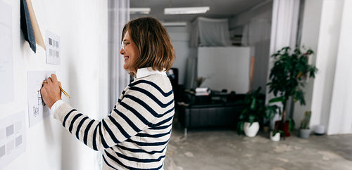 In the studio, the furniture designer writes notes while shaping new design ideas