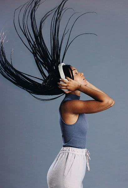 Ethnic girl flipping her braids while listening to music on headphones