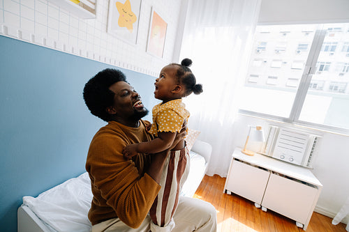 Father lifts daughter in bright cozy bedroom