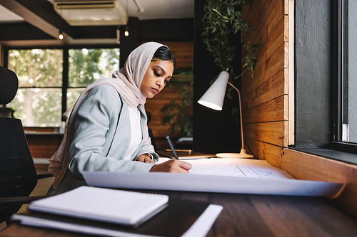 Creative Muslim designer working with drawings in an office