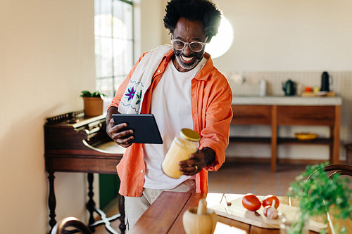 Mature man cooking a traditional Brazilian recipe with a digital tablet