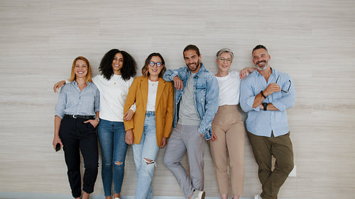 Team of young and ambitious business professionals stand together in the office, smiling at the camera