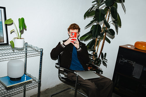 A man checks his smartphone in a modern home interior.
