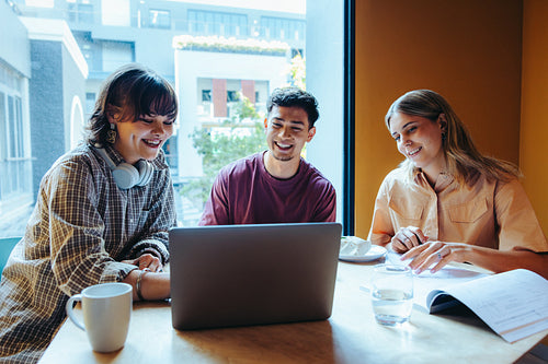 University students studying together at a campus cafe, collaborating on a group project and enjoying coffee
