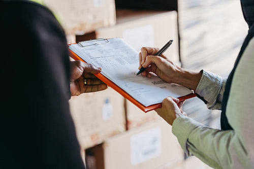Warehouse manager signing a bill of lading on a clipboard
