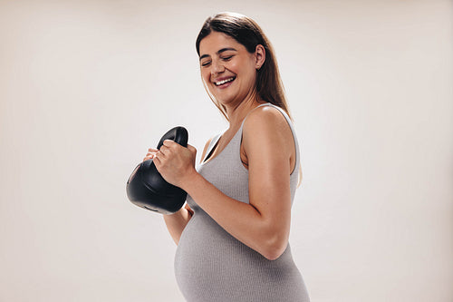 Happy pregnant woman exercising with a dumbbell and prioritizing prenatal wellness in studio