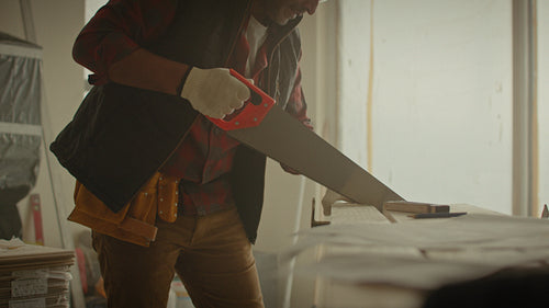 Man sawing wood plank during home renovation