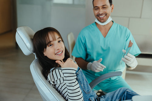 Child gives thumbs up to dentist from clinic chair