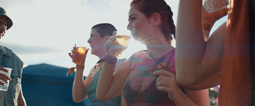Diverse group of friends enjoying drinks and laughter at an outdoor music festival