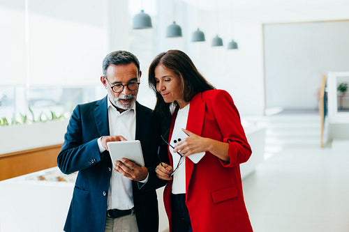 Senior management discussing business details using tablet in bright office setting