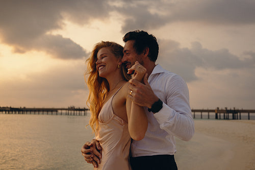 Serene sunset embrace: Elegant couple sharing a loving moment on the beach