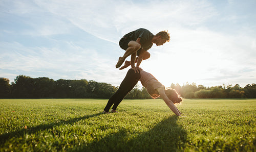 Fit couple doing acrobatic yoga exercise in park