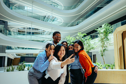 Group of colleagues taking a selfie in modern office setting