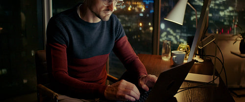 Businessman working late on laptop in city office